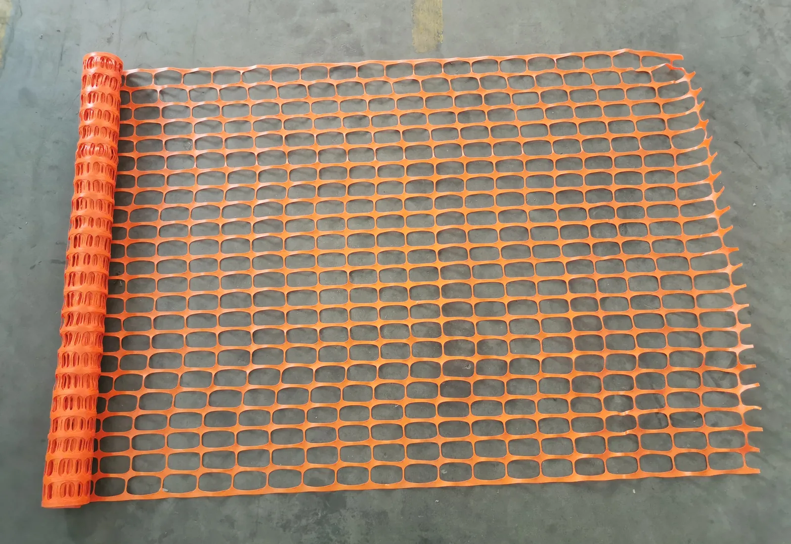 Orange HDPE plastic safety fence roll opened on a factory floor